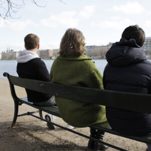 Mennesker sidder på en bænk og ser ud over Søerne i København.